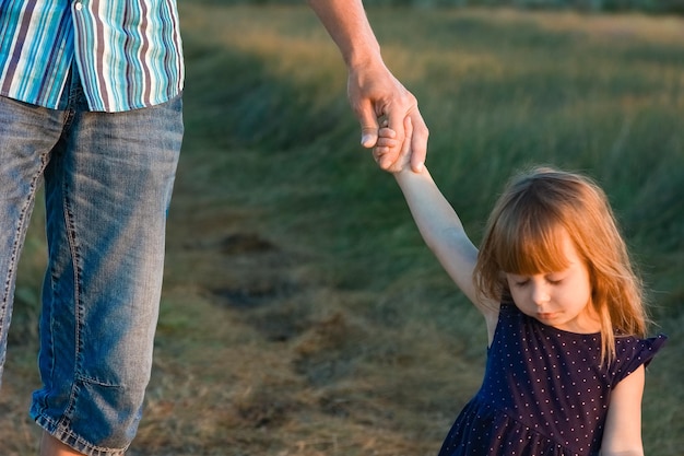 A Hands of a happy child and parent in nature in a park by the road