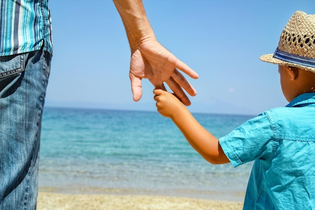 A hands of a happy parent and child by the sea in nature travel