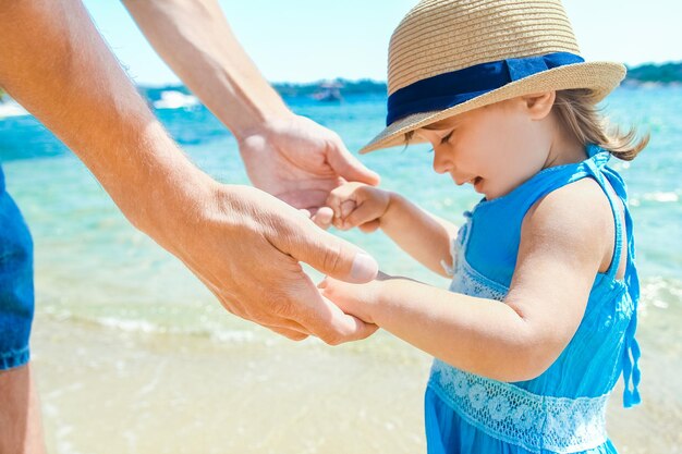 A Hands of a happy parent and child in nature by the sea on a journey background