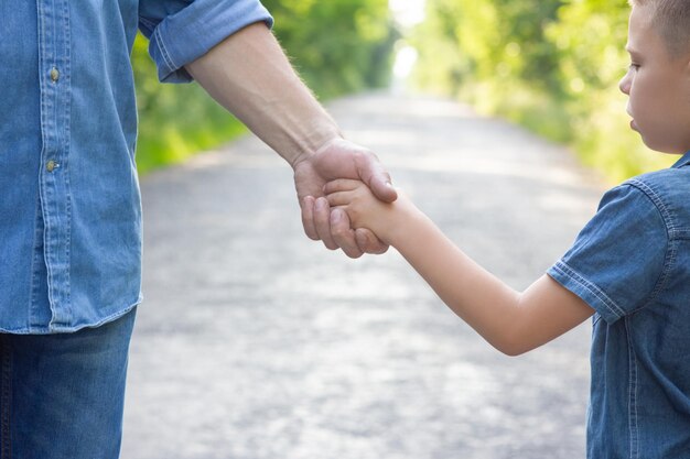 Foto a le mani di un genitore e di un bambino felici nella natura nel parco turistico