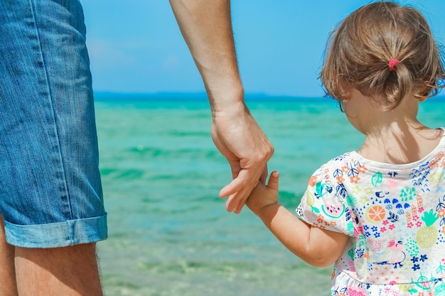 Hands of happy parent and child at sea greece background