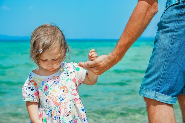 Hands of happy parent and child at sea greece background