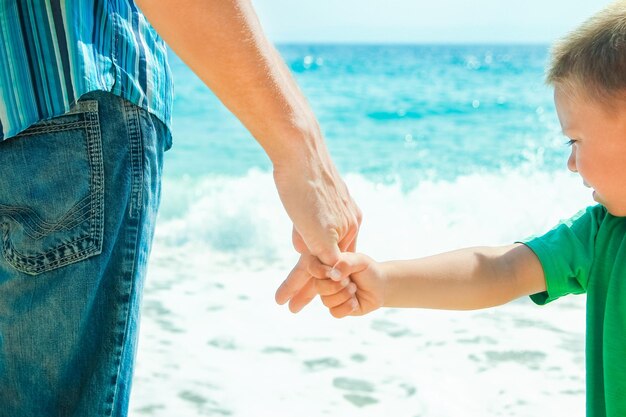 A Hands of a happy parent and child on the seashore on a journey trip in nature