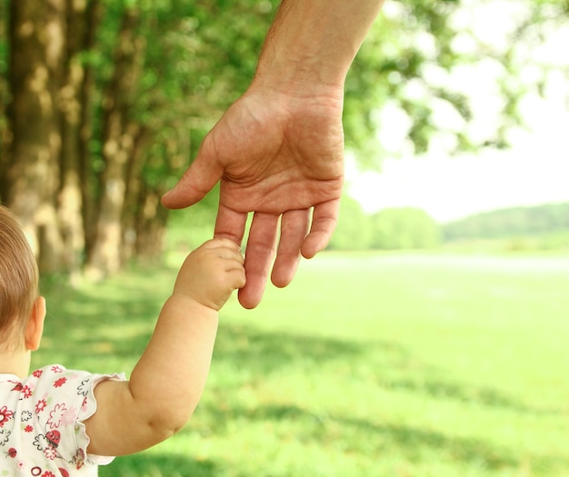 Hands of a happy parent and  little child in nature