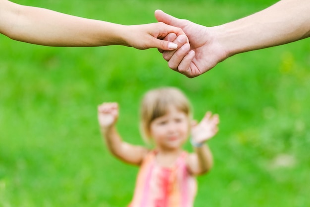 Photo hands happy parents and child outdoors in the park