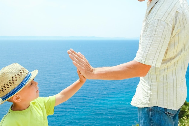 ギリシャの旅行の背景に海で幸せな親と子の手