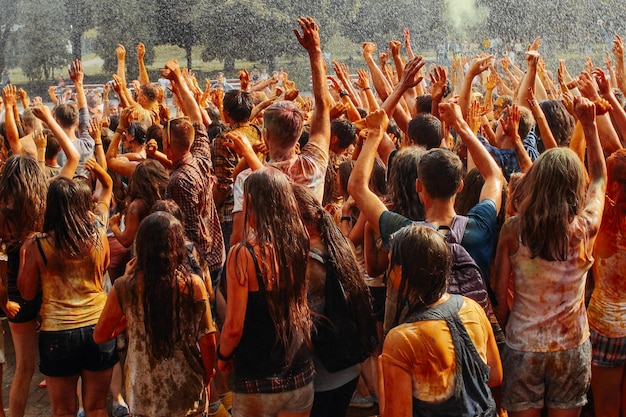 Hands and happy people crowd partying under rain at holi fest festival of colors in summer amazing moment