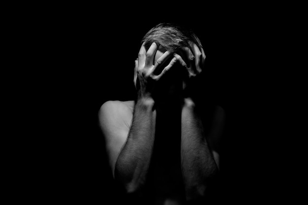 Hands on head, black and white dramatic photo of a man