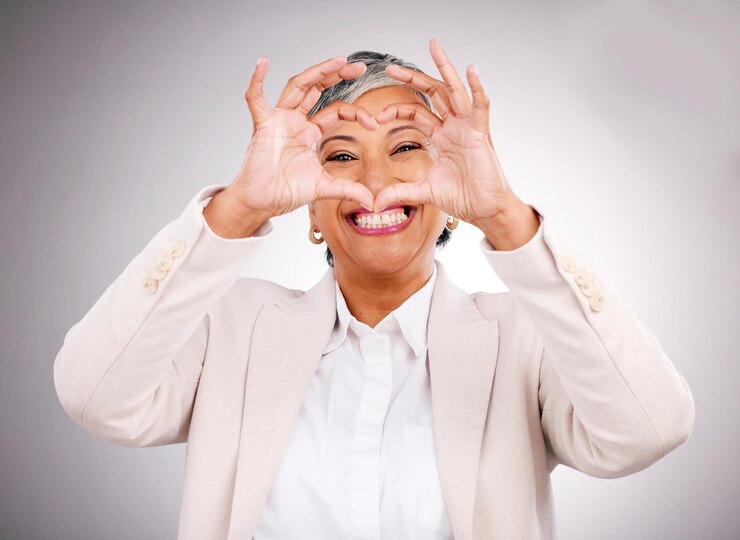 Photo hands in heart business and portrait of woman for success support and charity in studio success corporate and face of mature person with hand gesture for love yes and emoji on gray background