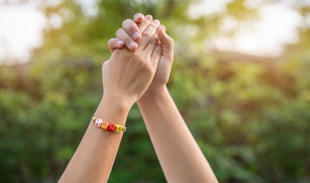 Mani e cuori insieme primo piano di una coppia di innamorati che si tengono per mano indossando un braccialetto del polso love