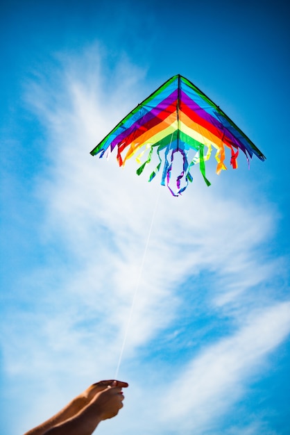 Photo hands hold beautiful and bright rainbow colorful kite