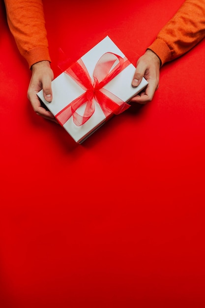 Photo hands hold beautiful christmas gift box. merry christmas.red background.copy space text banner card