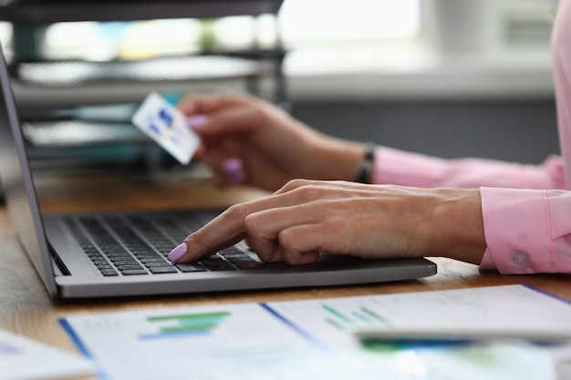 Hands hold credit card and enter info into laptop