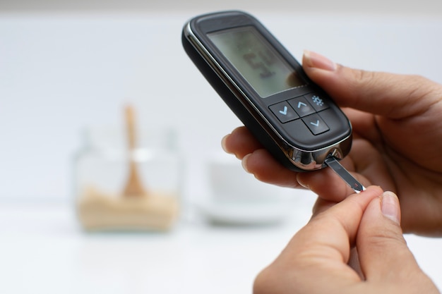 Hands hold the glucose test machine to test blood glucose levels