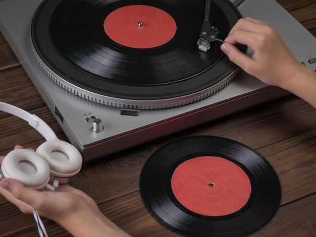 Hands hold the headphones and place the needle on the vinyl disc