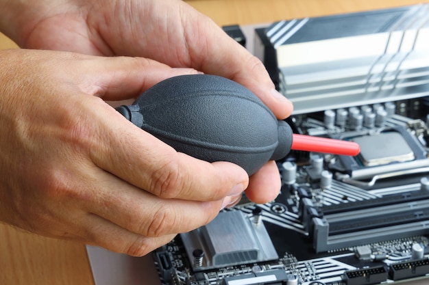 Foto le mani tengono il ventilatore dell'uragano per soffiare aria e soffia via la polvere sull'elettronica