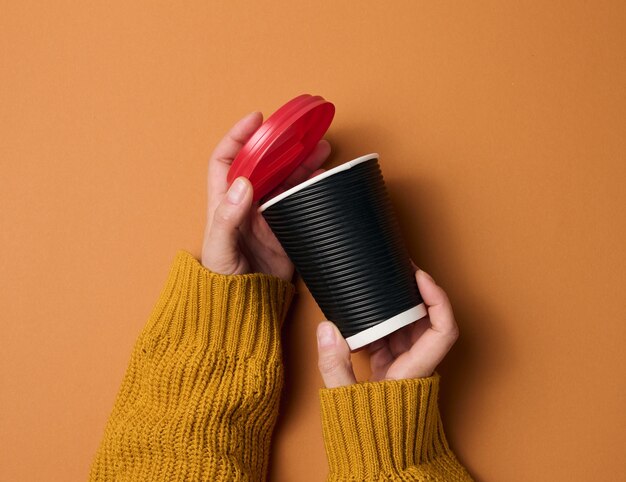 Hands hold paper cardboard brown cup for coffee. eco-friendly\
tableware