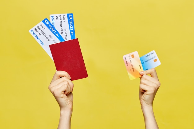 Hands hold a passport with tickets and credit cards