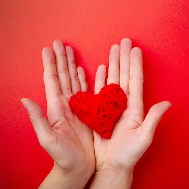 Hands hold red heart on red background. St. Valentine's day concept