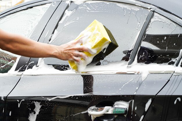 Hands hold sponge for washing car