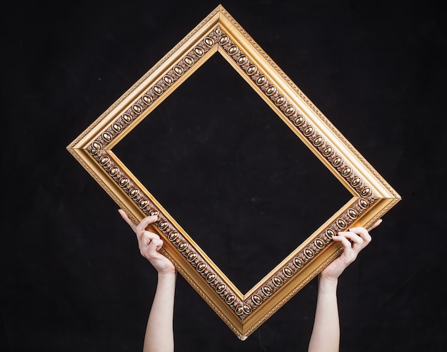 Hands hold vintage frame on black background