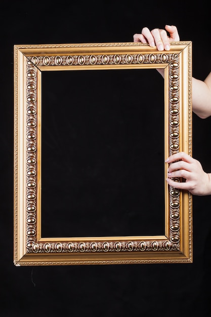 Hands hold vintage frame on black background