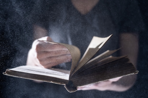 Hands hold Vintage open Book Glows on black background