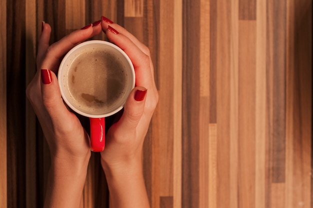 Hands holdig cup on wooden table