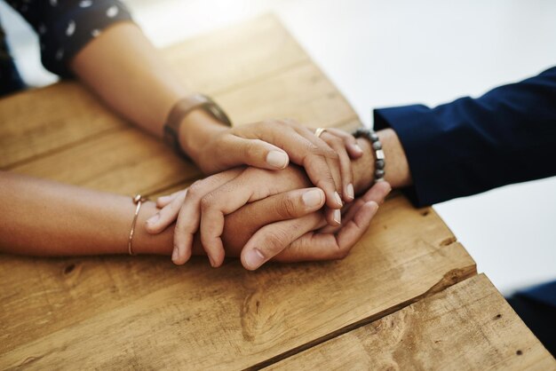 Photo hands holding abuse victim in a therapy session for support and comfort by a professional psychologist on a wooden table kind and caring therapist touching to show care and affection in counseling