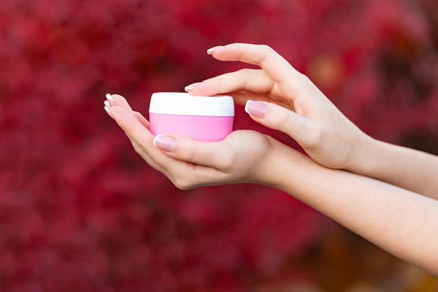 Hands holding and applying cream jar for skincare cosmetology