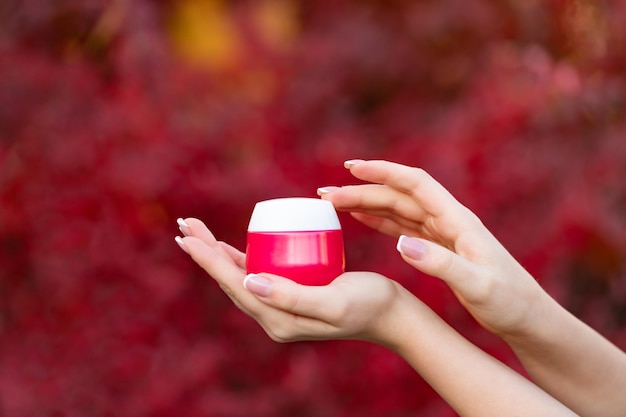 Hands holding and applying cream jar for skincare presenting product