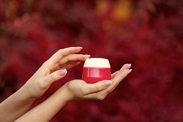 Hands holding and applying cream jar for skincare presenting product