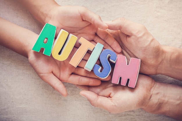 Photo hands holding autism word,  mental health concept, world autism awareness day