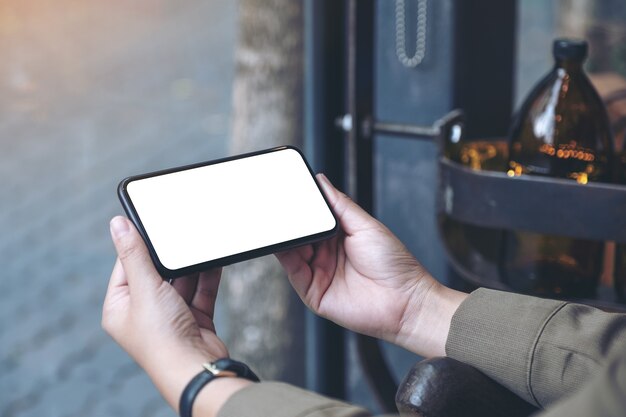 hands holding black mobile phone with blank desktop screen horizontally