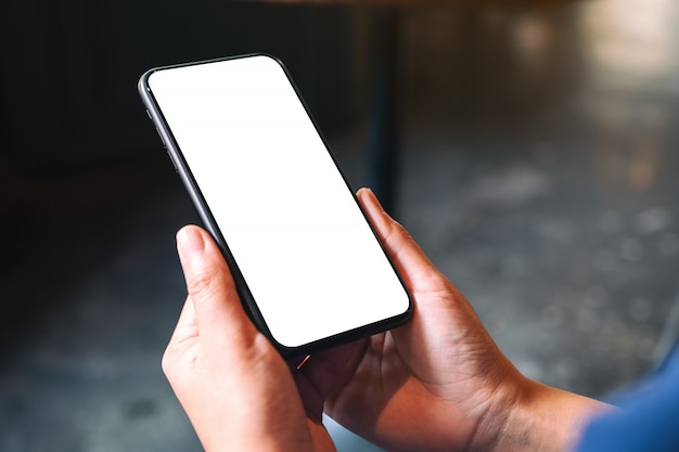 hands holding black mobile phone with blank desktop screen