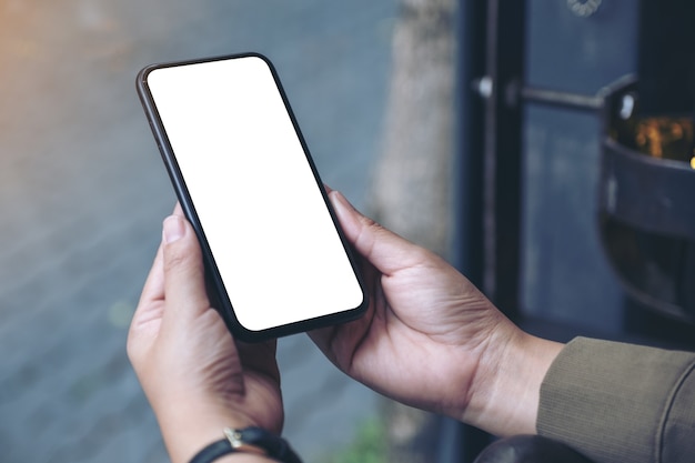 hands holding black mobile phone with blank white desktop screen