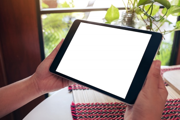 Hands holding black tablet pc with blank white desktop screen