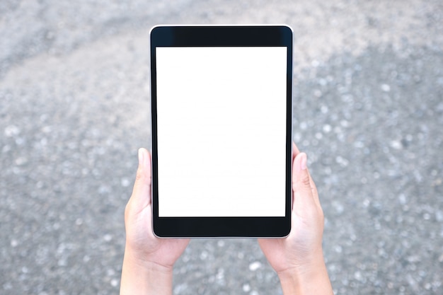 Hands holding black tablet pc with blank white screen