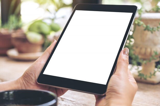 Hands holding black tablet with blank white screen