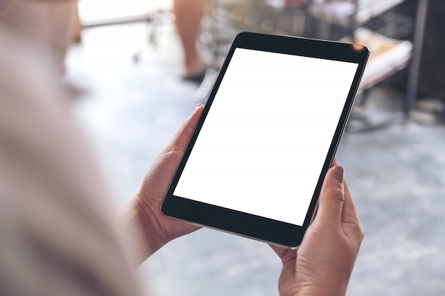 Hands holding black tablet with white blank desktop screen