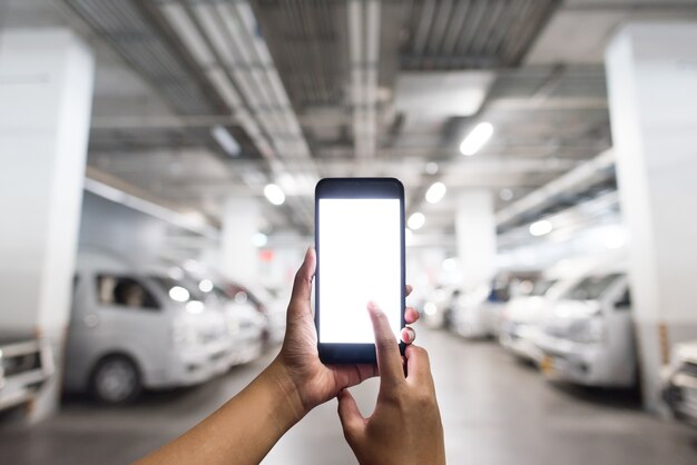 hands holding the blank white screen smartphone in the parking lot