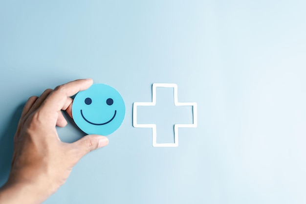 Hands holding blue happy smile face for medical care concept mental health positive thinking Hands holding blue happy smile face for medical care concept mental health positive thinking