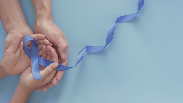 Photo hands holding blue ribbon, prostate cancer awareness, men health awareness