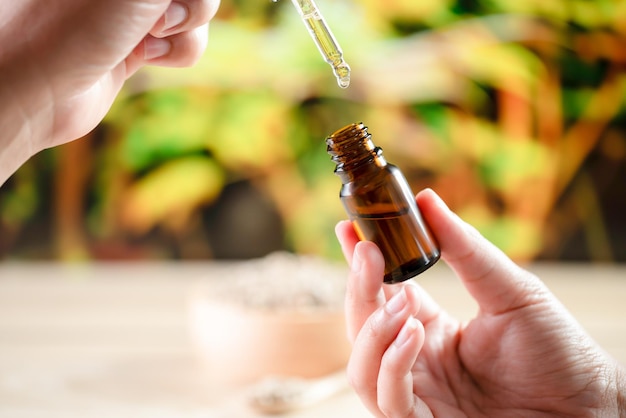 Hands holding a bottle of legalized CBD oil and its dropper lid with hemp leaf