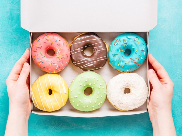 Hands holding box with donuts