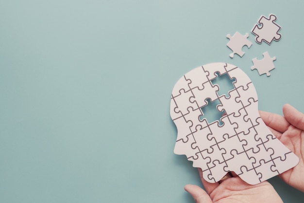 Photo hands holding brain with puzzle paper cutout, world mental health day