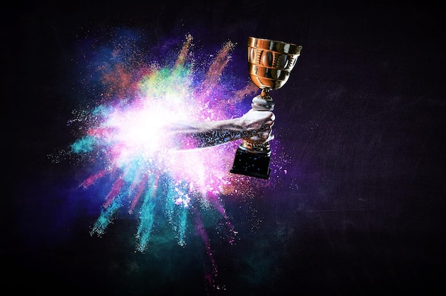 Photo hands holding champion cup on colourful splashes background. mixed media