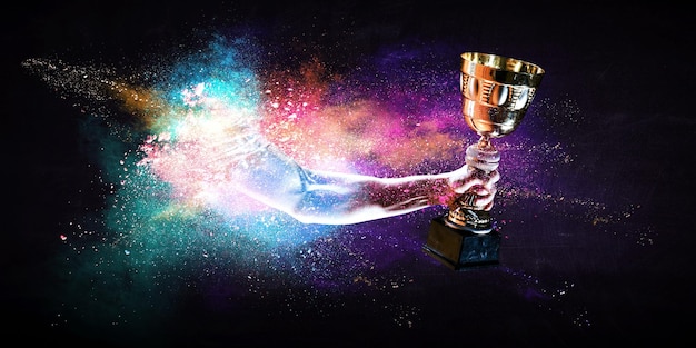 Photo hands holding champion cup on colourful splashes background. mixed media