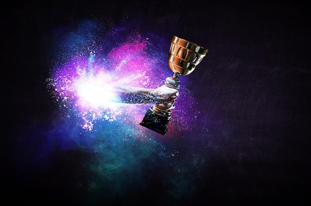 Photo hands holding champion cup on colourful splashes background. mixed media