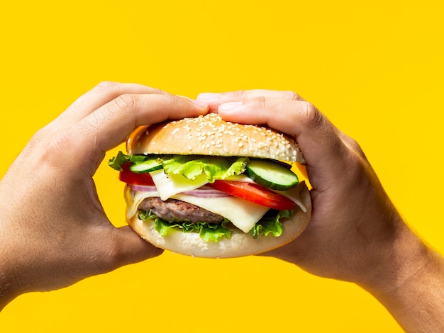 Photo hands holding cheeseburger with seeds